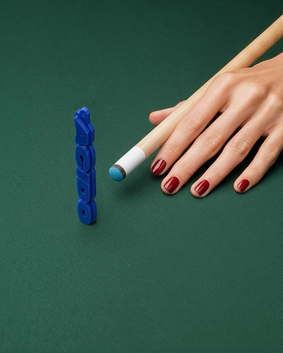 Portachiavi blu con scritta ACIDO in bilico su tavolo da biliardo con mano e stecca affianco