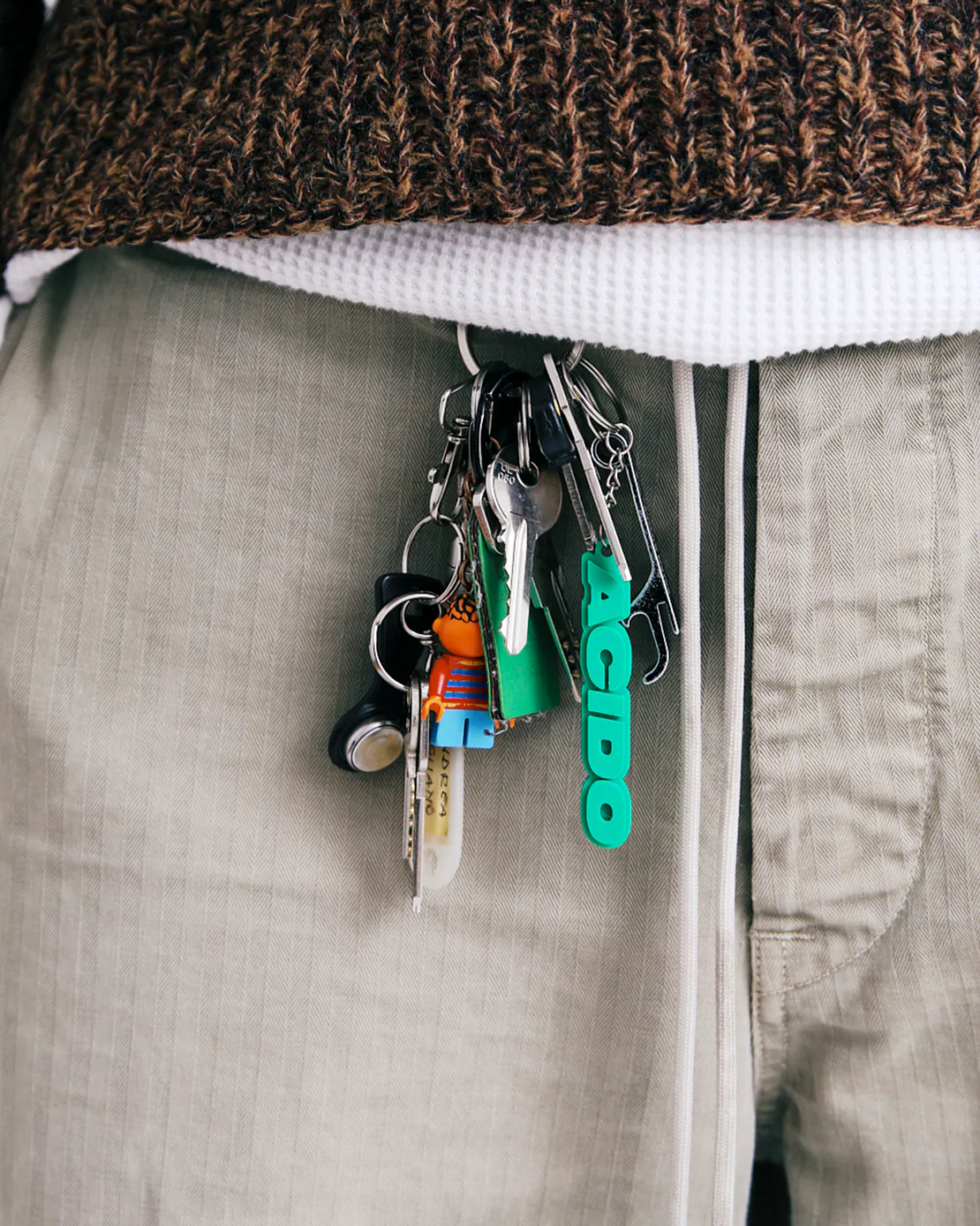 Portachiavi verde con scritta ACIDO e mazzo di chiavi agganciato a pantaloni