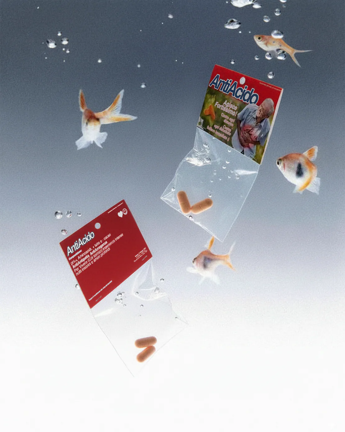 Due bustine di Antiacido Pills immerse in acqua, che fluttuano tra bolle e pesci rossi.