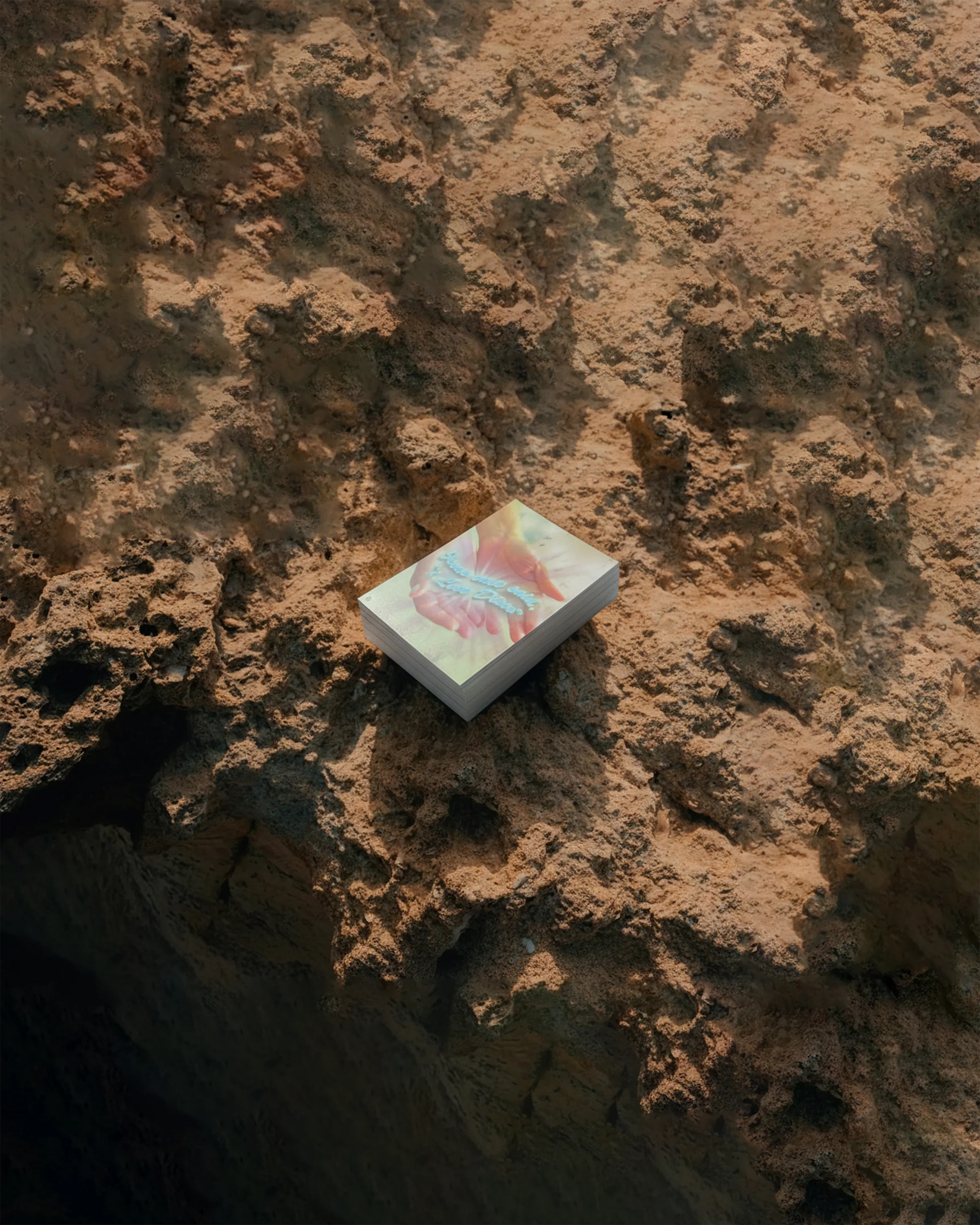 Mazzo di cartoline “Jesus Loves Disco” posato su una roccia color ocra.