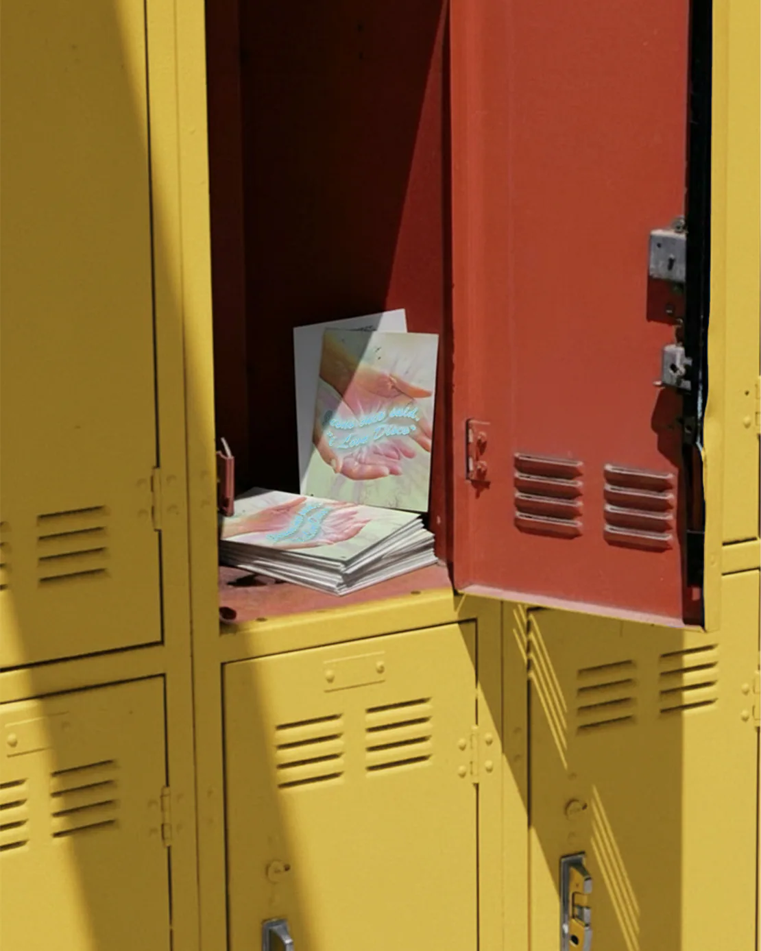 Cartoline “Jesus Loves Disco” dentro un armadietto scolastico giallo e rosso aperto.