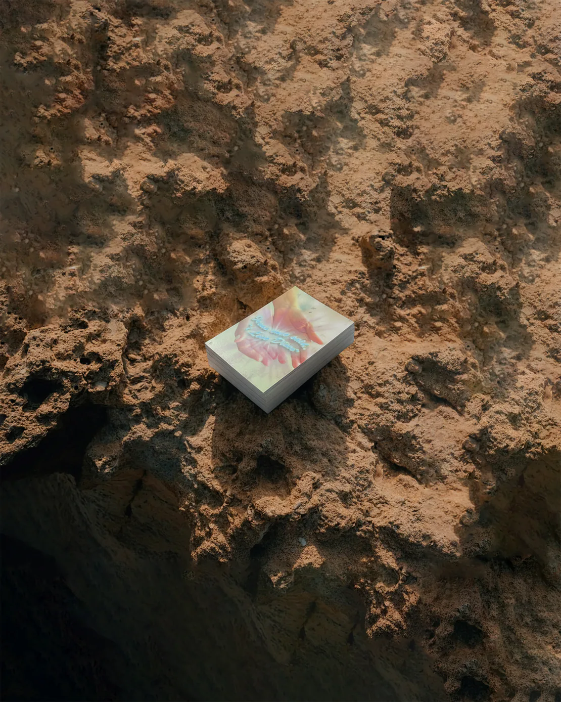 Mazzo di cartoline “Jesus Loves Disco” posato su una roccia color ocra.