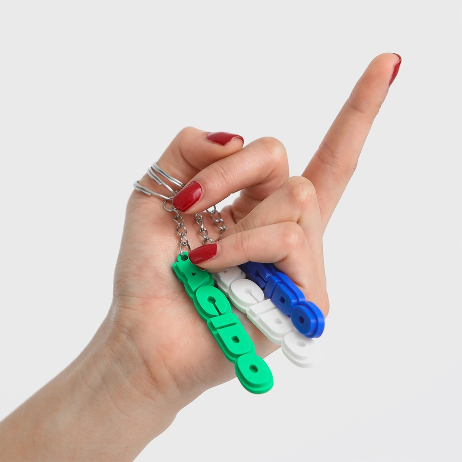 Una mano che tiene diversi portachiavi 'ACIDO' di vari colori, tra cui verde, blu e bianco.