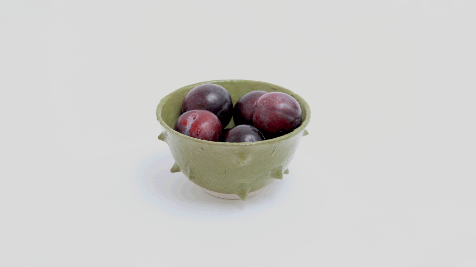 GIF Ramen Bowl verde di Acidolattico Magazine contenente prugne rosse e viola, evidenziando il design artigianale e l'uso funzionale del prodotto.