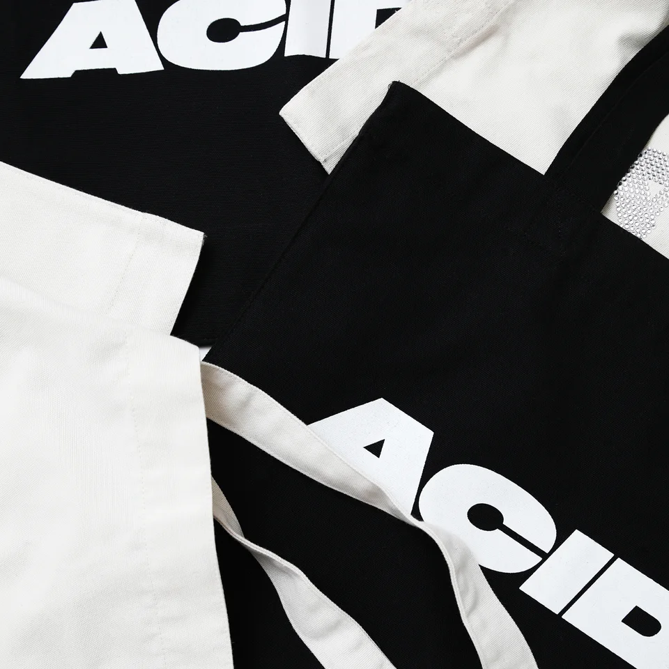 Dettaglio delle maniglie della totebag nera con il logo 'ACIDO', evidenziando la qualità del materiale.