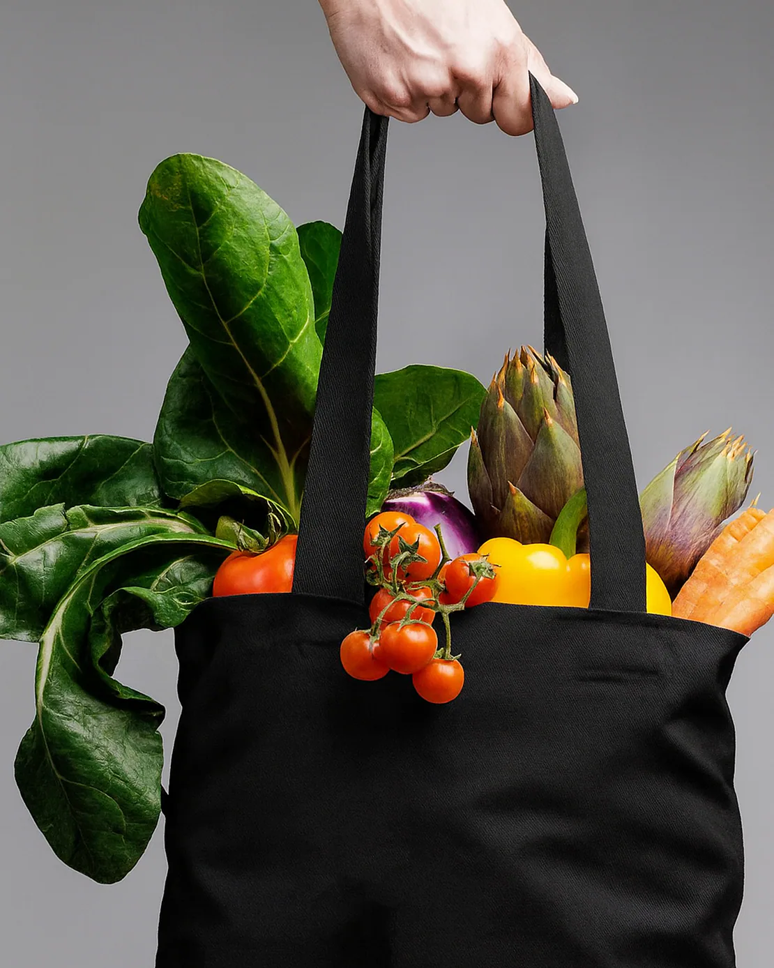Totebag nera con scritta bianca ACIDO piena di verdure fresche come pomodori, carote, peperoni e bietole.